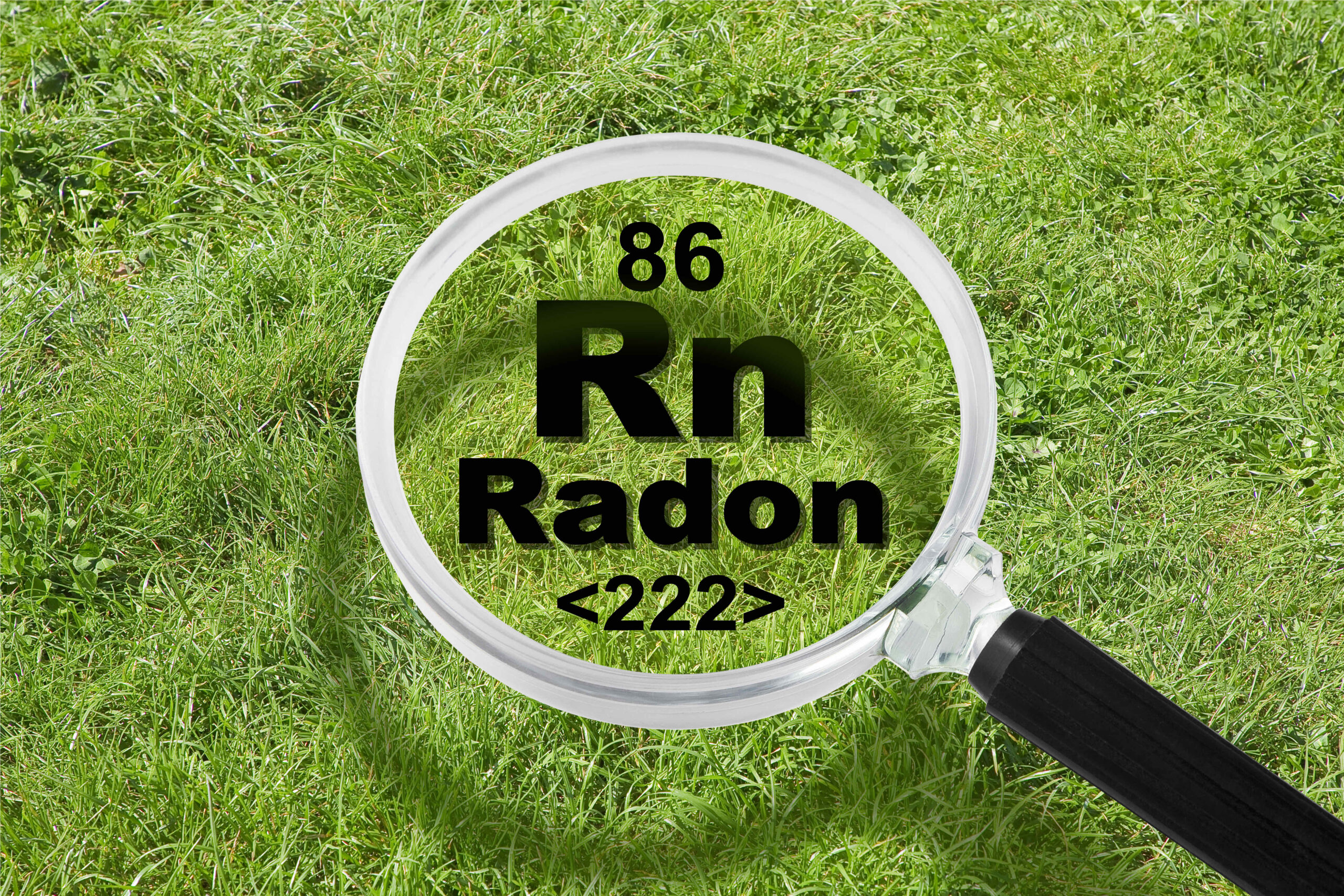 The dangerous radioactive natural radon gas under the ground - concept with periodic table of the elements, magnifying lens and green grass area