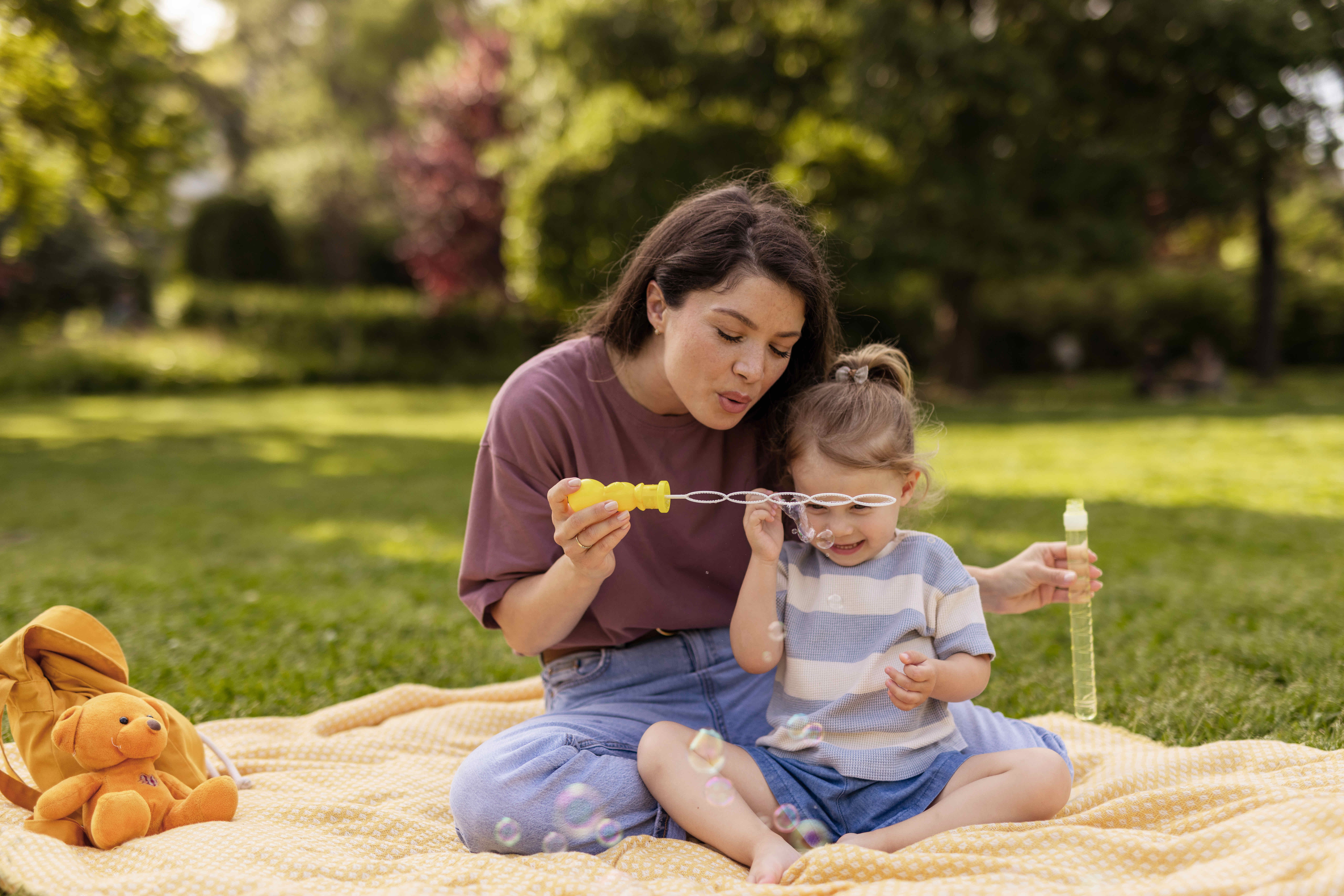 Happy Mother and Daughter Playing with Bubbles Outdoors